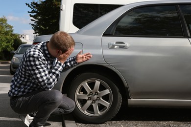 Stressed man near car with scratch outdoors
