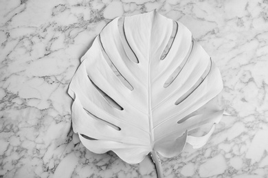 Photo of Painted tropical Monstera leaf on marble background, top view