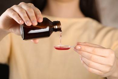 Woman pouring cough syrup into dosing spoon, closeup