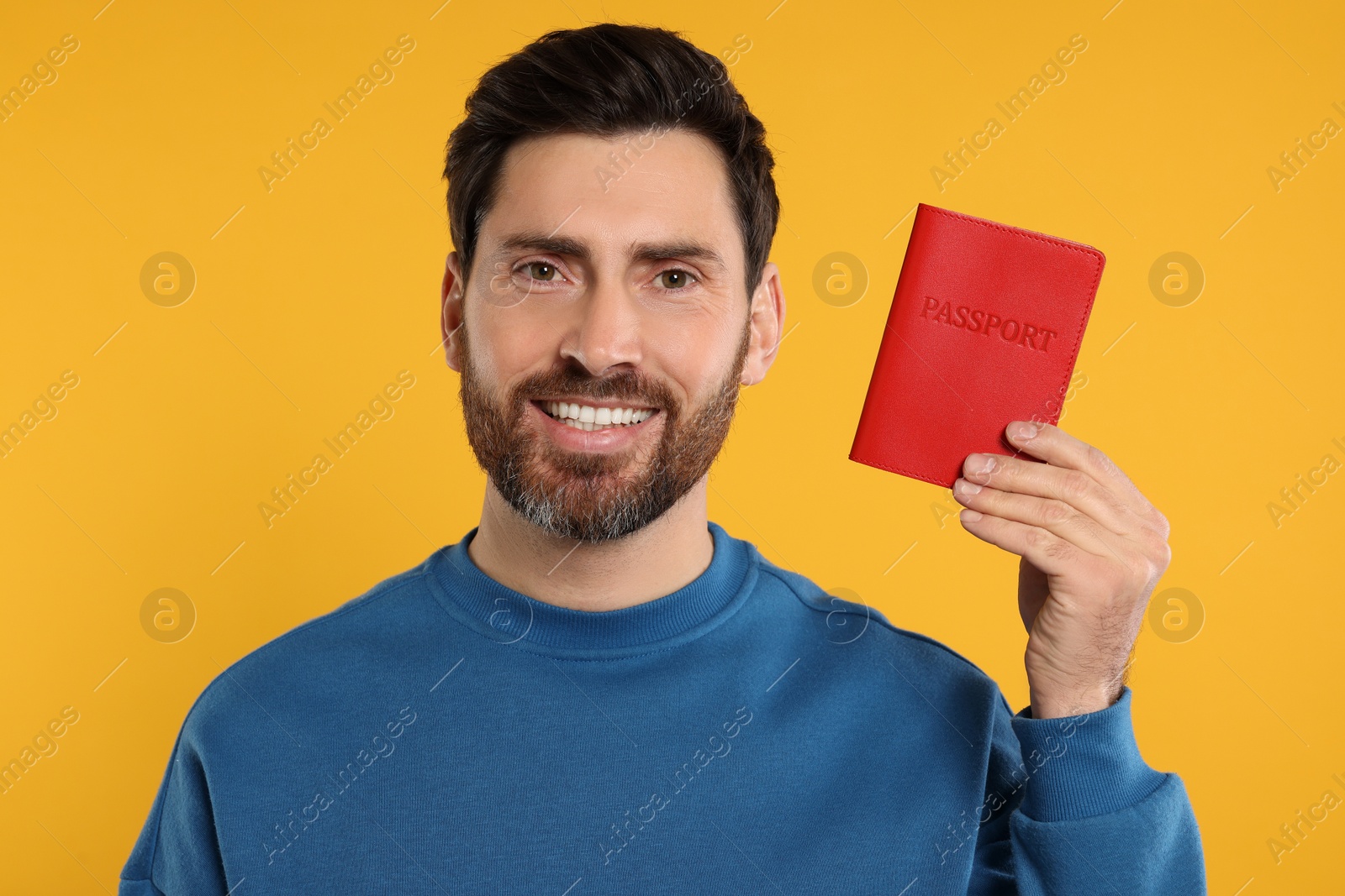 Photo of Immigration. Happy man with passport on orange background