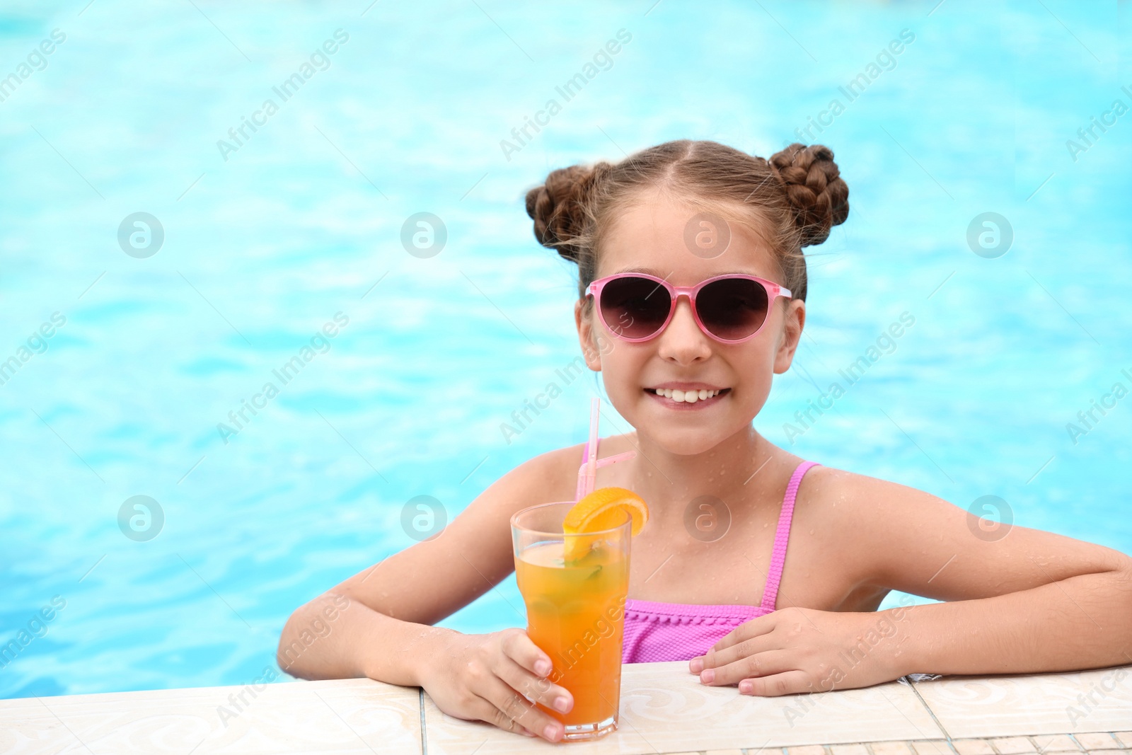 Photo of Little girl with cocktail in pool on sunny day