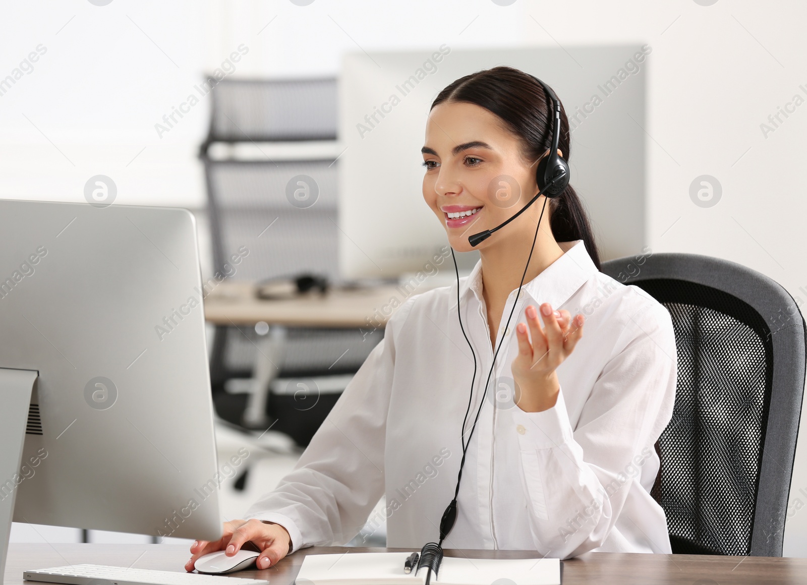 Photo of Hotline operator with headset working on computer in office