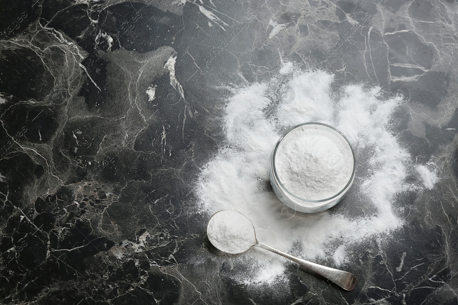 Photo of Jar and spoon with baking soda on grey background, top view. Space for text