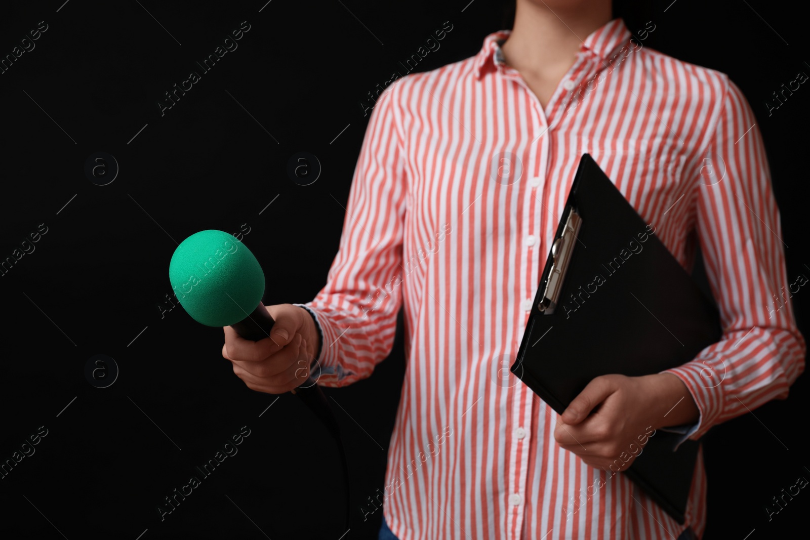 Photo of Journalist with microphone and clipboard on black background, closeup