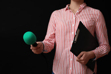 Photo of Journalist with microphone and clipboard on black background, closeup