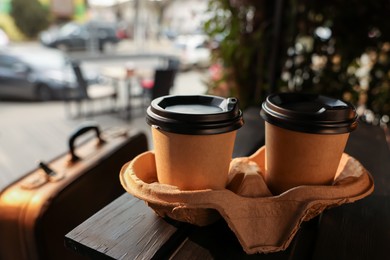 Photo of Paper coffee cups on wooden table in outdoor cafe.