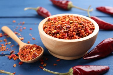 Photo of Chili pepper flakes and pods on blue wooden table, closeup