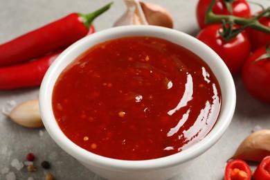 Photo of Spicy chili sauce in bowl on grey table, closeup