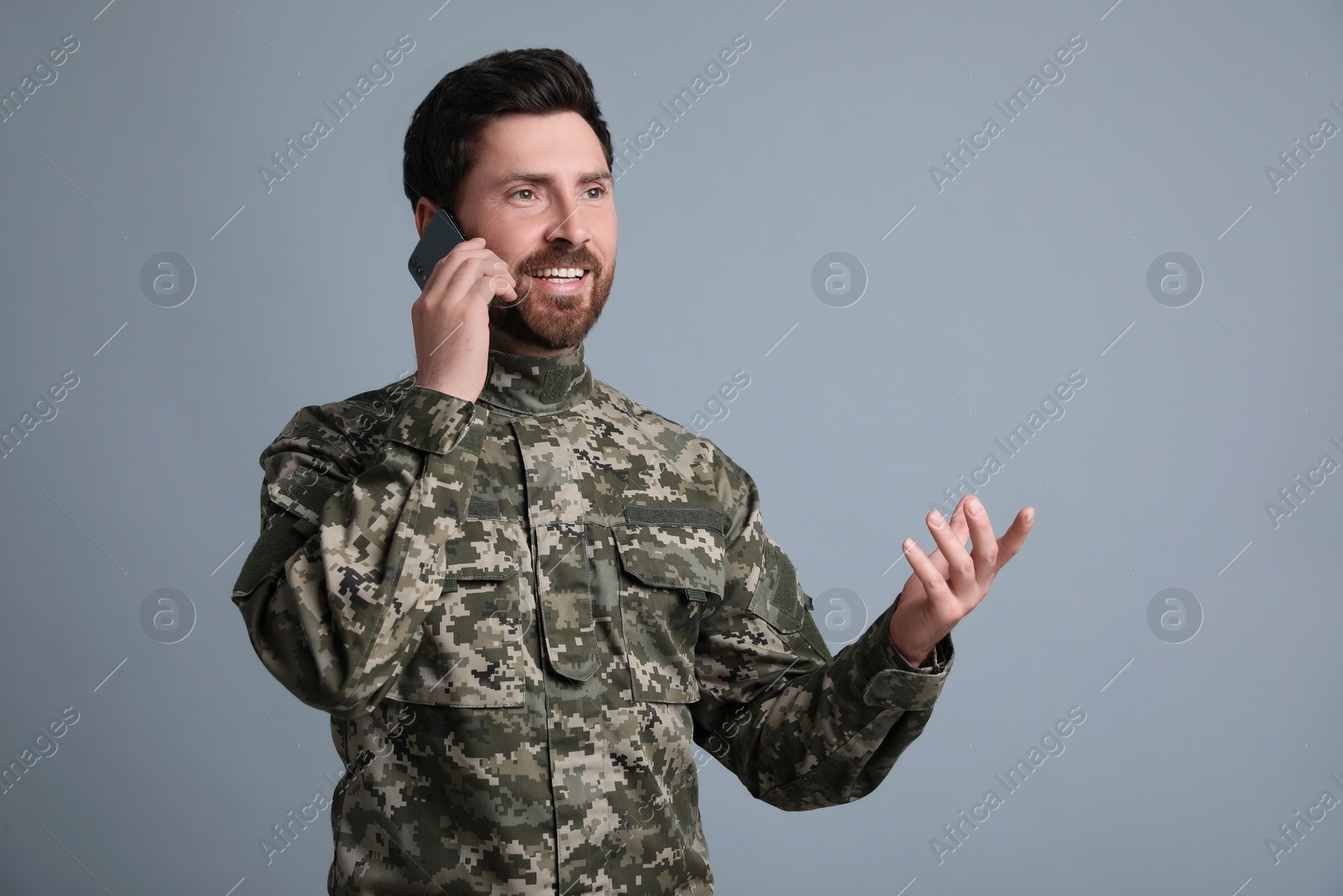 Photo of Happy soldier talking on phone against light grey background. Military service