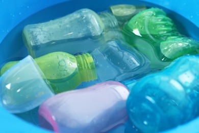 Photo of Light blue basin with baby bottles, closeup