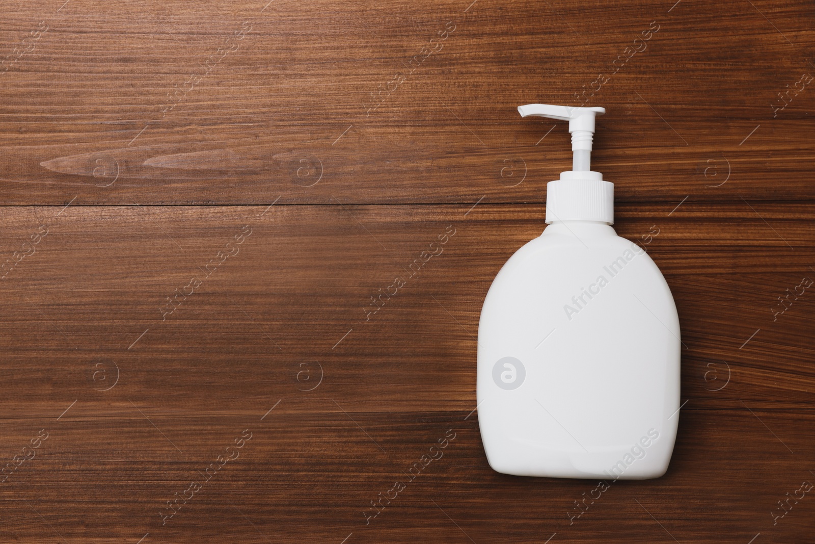 Photo of Dispenser of liquid soap on wooden table, top view. Space for text