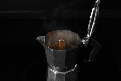 Photo of Hot brewed coffee in moka pot on stove, closeup