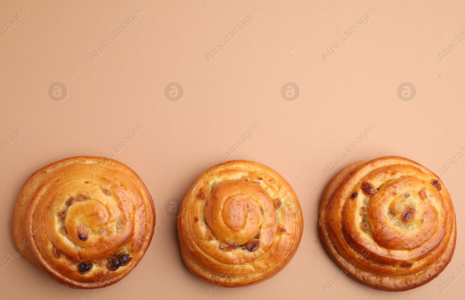 Photo of Delicious rolls with raisins on beige background, flat lay and space for text. Sweet buns