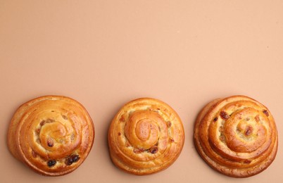 Delicious rolls with raisins on beige background, flat lay and space for text. Sweet buns