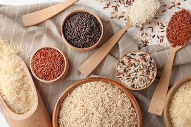 Flat lay composition with brown and other types of rice on wooden background