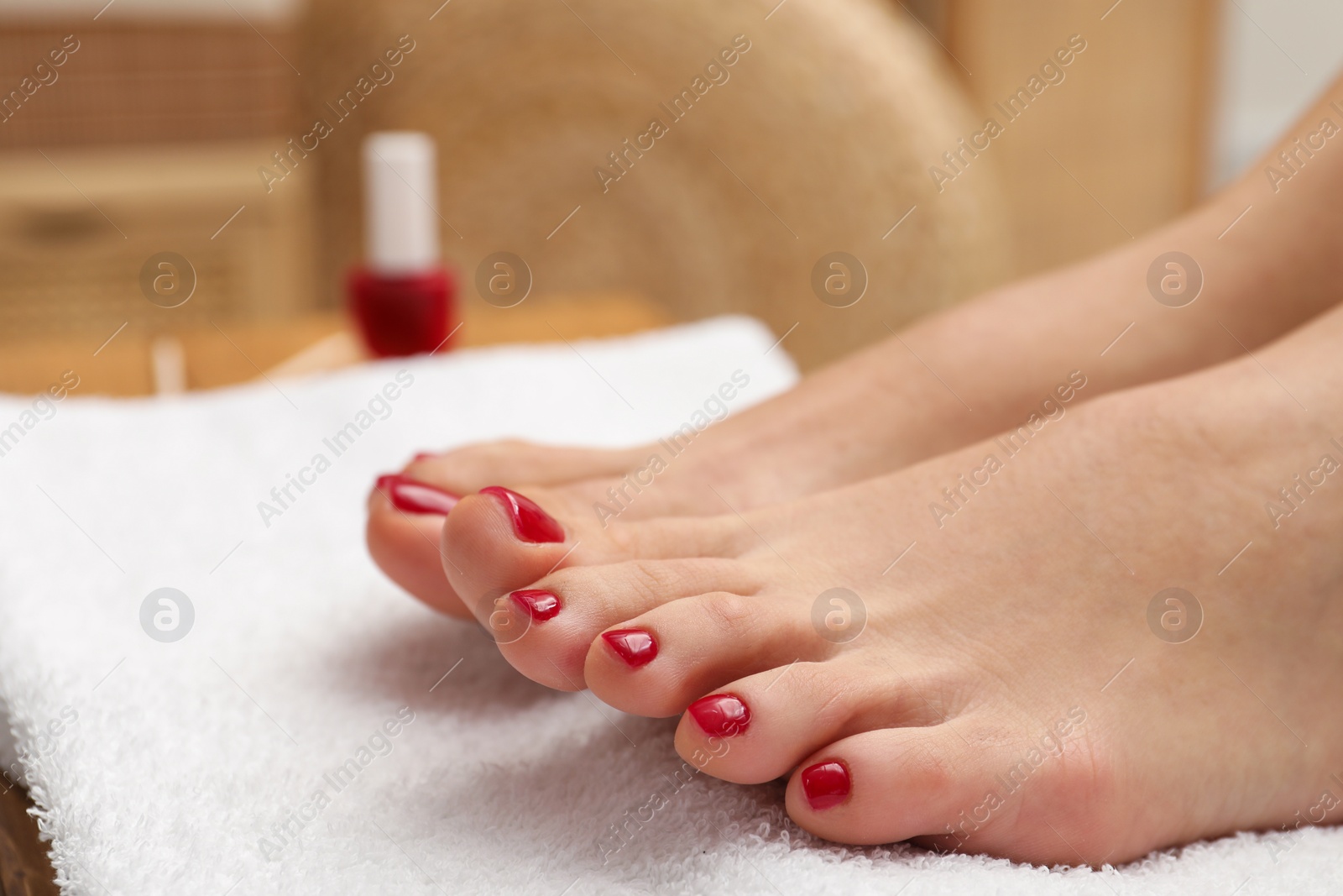 Photo of Woman with stylish red toenails after pedicure procedure on white terry towel indoors, closeup