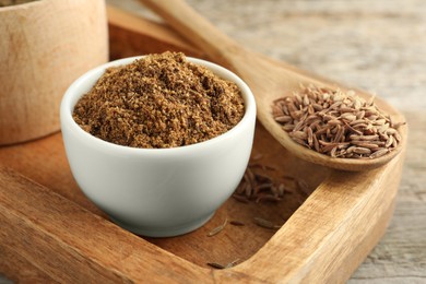 Caraway (Persian cumin) powder and dry seeds on wooden table, closeup