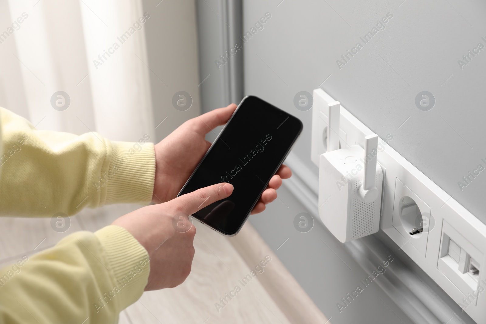Photo of Woman using smartphone for wireless Wi-Fi repeater indoors, closeup