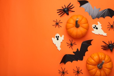 Photo of Flat lay composition with cardboard bats, pumpkins, ghosts and spiders on orange background, space for text. Halloween celebration