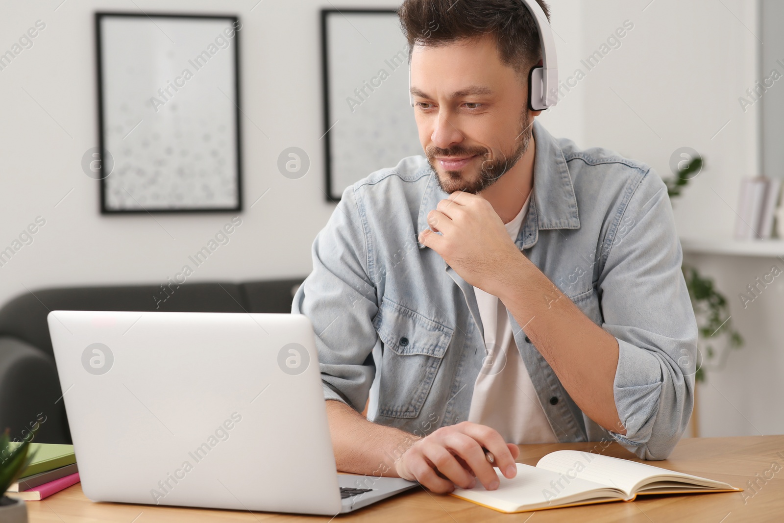 Photo of Man in headphones studying on laptop at home. Online translation course