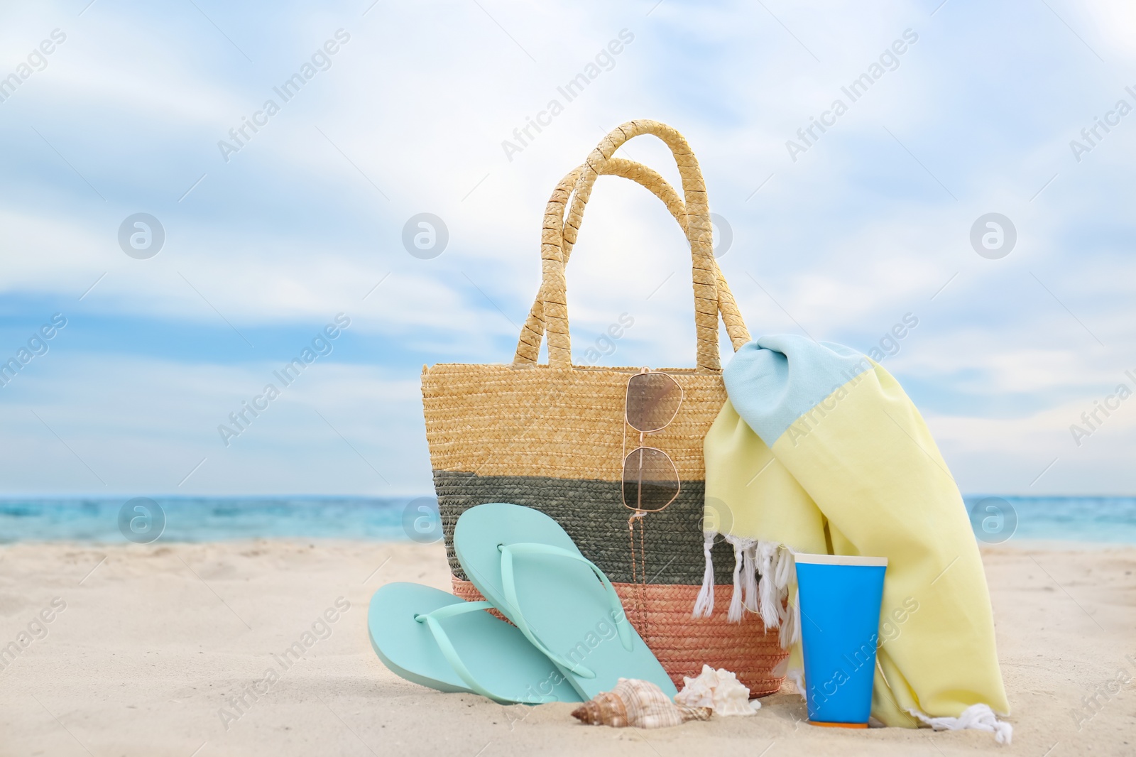 Photo of Different stylish beach objects and seashells on sand near sea