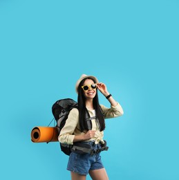 Photo of Happy female tourist with backpack on light blue background