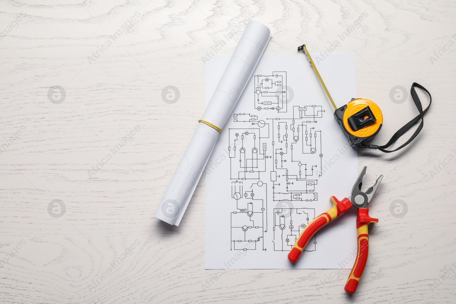 Photo of Wiring diagram, pliers and tape measure on white wooden table, flat lay. Space for text