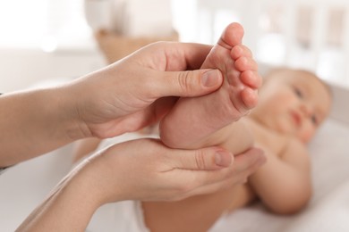 Photo of Mother massaging her cute baby with oil at home, closeup