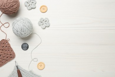 Photo of Flat lay composition with knitting threads and crochet hook on white wooden table, space for text