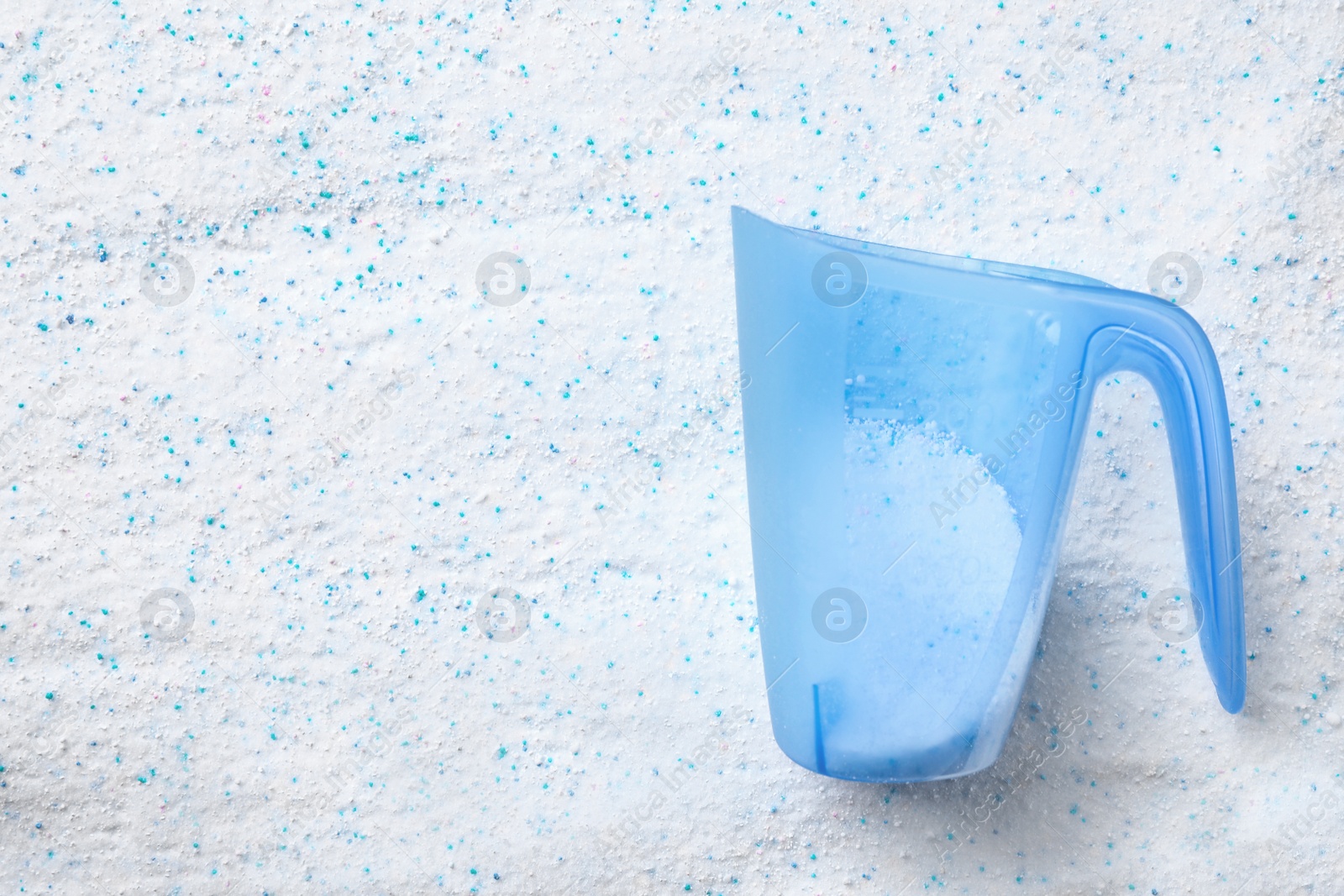 Photo of Measuring cup with laundry detergent, top view. Space for text