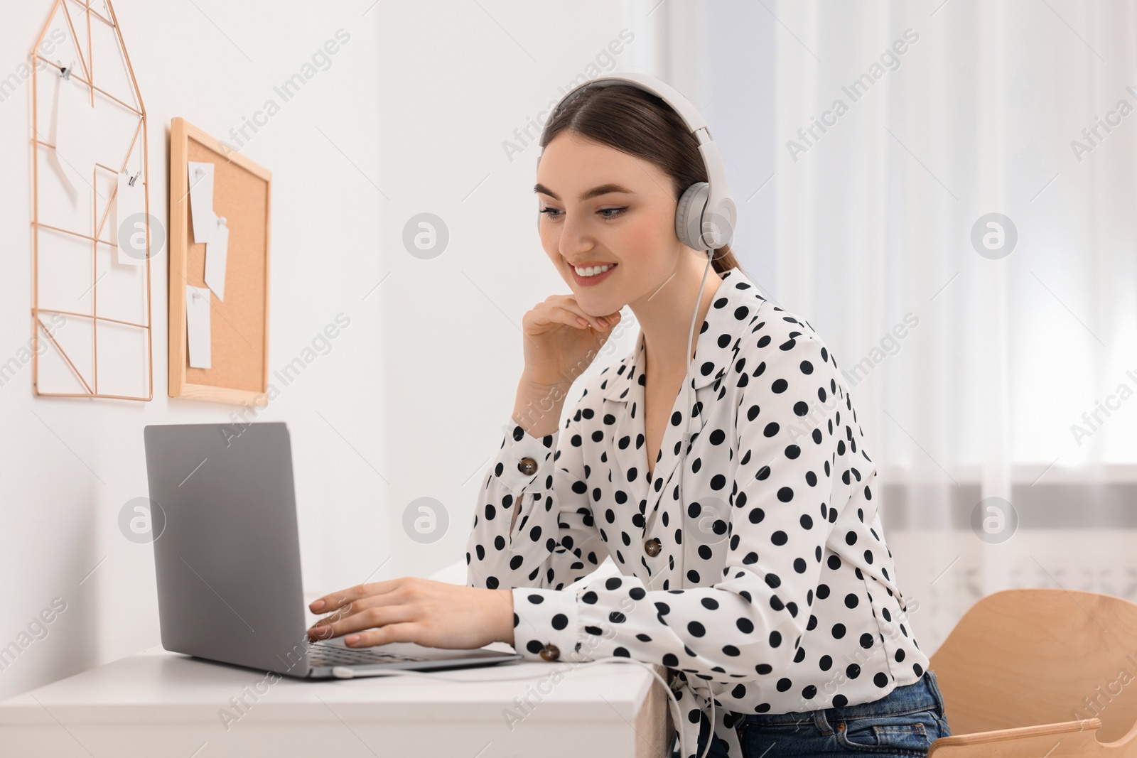 Photo of E-learning. Young woman using laptop during online lesson at table indoors