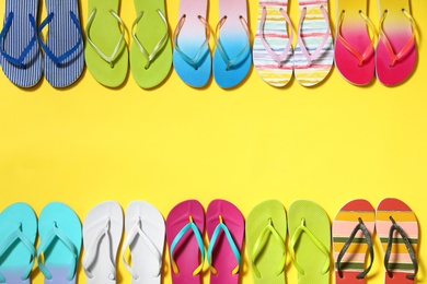 Photo of Different flip flops and space for text on yellow background, flat lay. Summer beach accessories