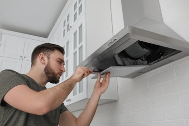 Photo of Man repairing modern cooker hood in kitchen