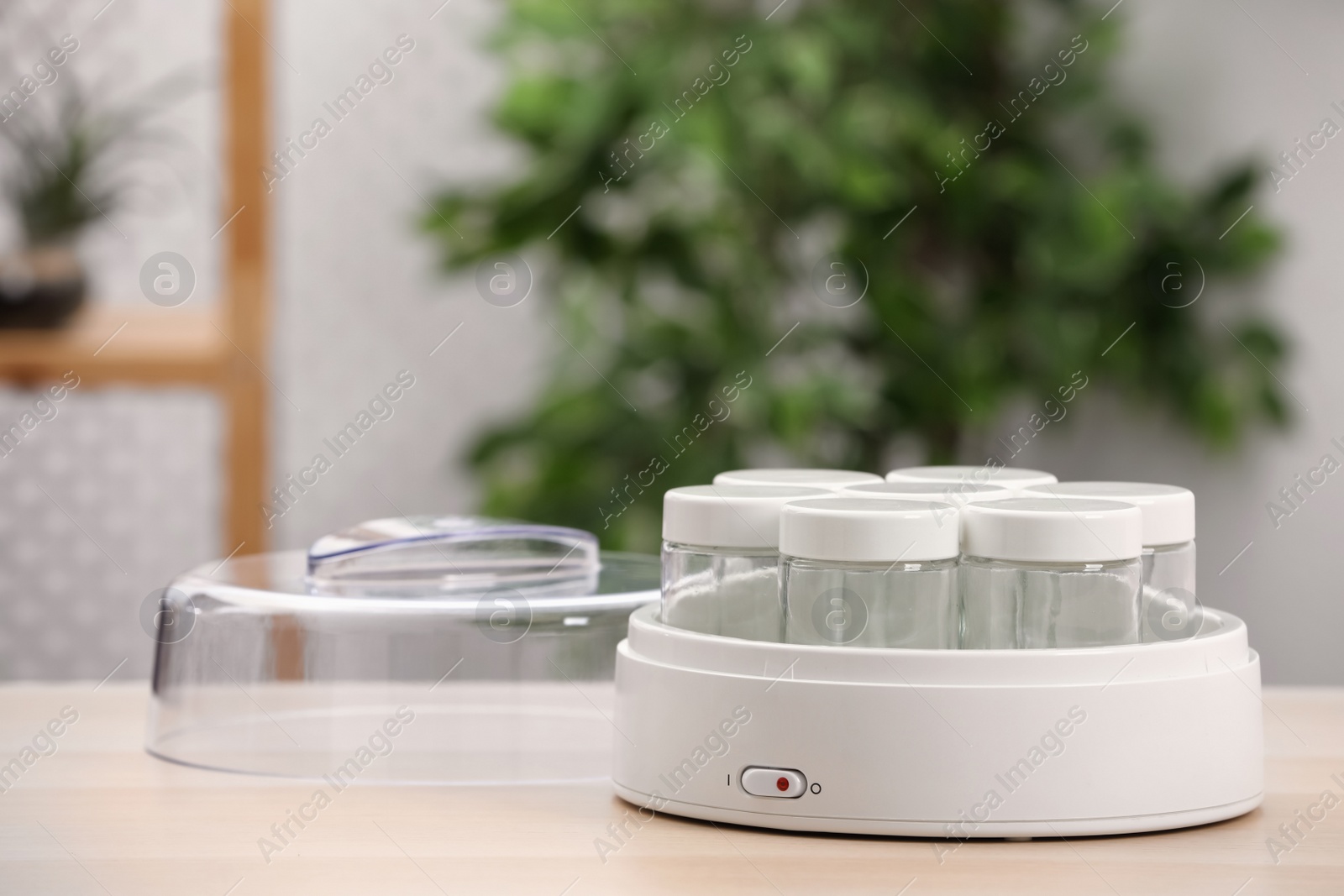 Photo of Modern yogurt maker with empty jars on table indoors. Space for text