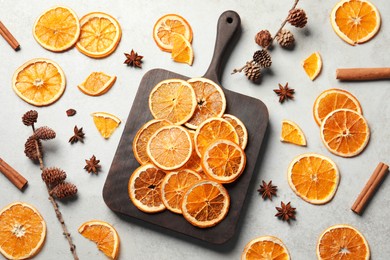 Photo of Dry orange slices, cinnamon sticks and anise stars on light grey table, flat lay