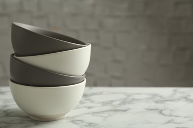 Stylish empty ceramic bowls on white marble table, space for text. Cooking utensils