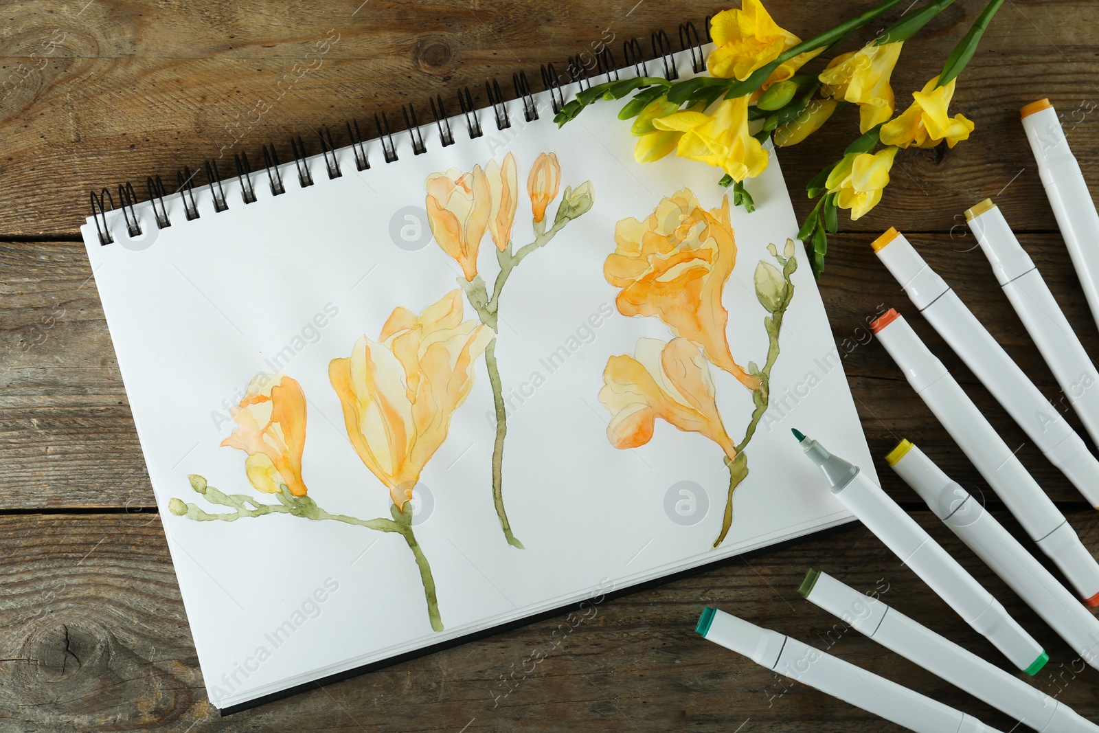 Photo of Flat lay composition with beautiful drawing of freesia flowers in sketchbook on wooden table