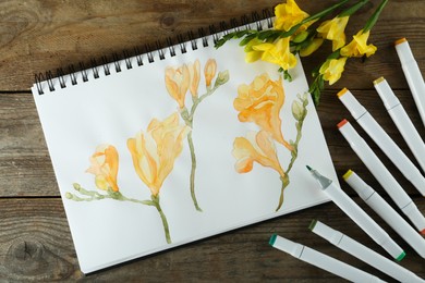 Photo of Flat lay composition with beautiful drawing of freesia flowers in sketchbook on wooden table