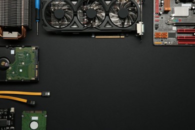 Photo of Graphics card and other computer hardware on black background, flat lay. Space for text