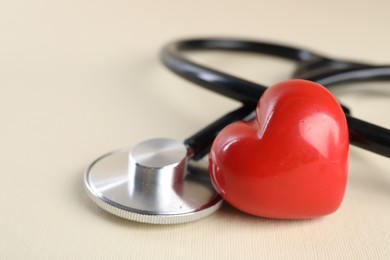 Photo of Stethoscope and red heart on beige background