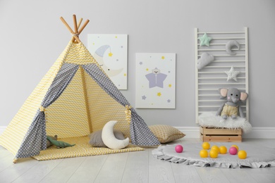 Photo of Stylish child's room interior with adorable paintings and play tent
