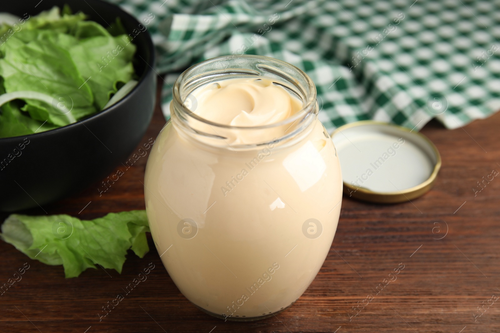 Photo of Jar of delicious mayonnaise and fresh salad on wooden table