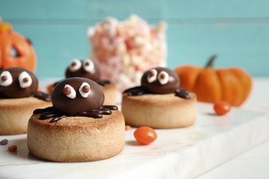 Photo of Delicious biscuit with chocolate spider on white table, closeup. Halloween celebration