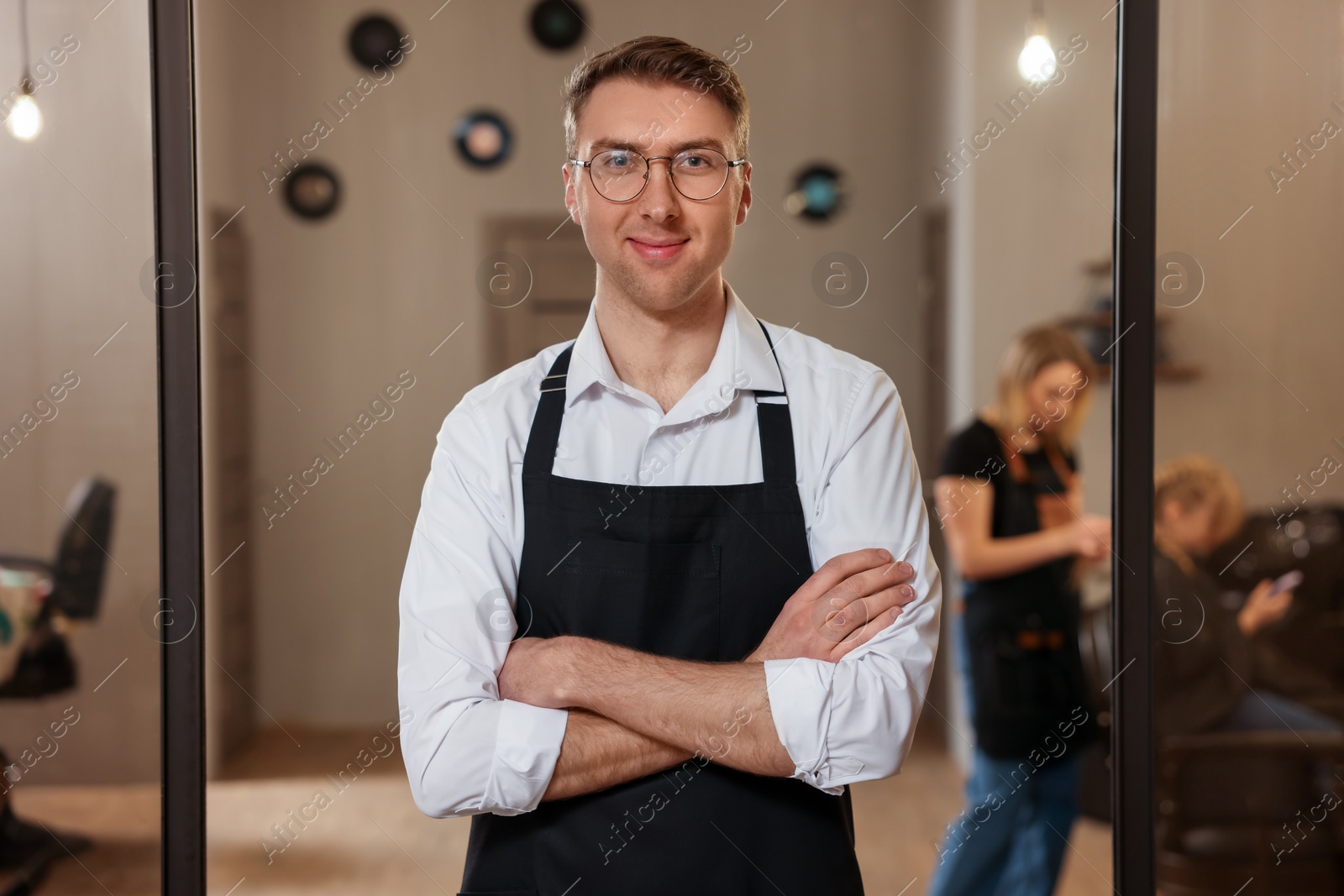 Photo of Portrait of professional hairdresser wearing apron in beauty salon