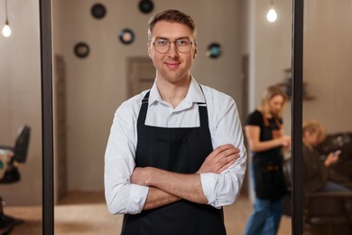 Photo of Portrait of professional hairdresser wearing apron in beauty salon