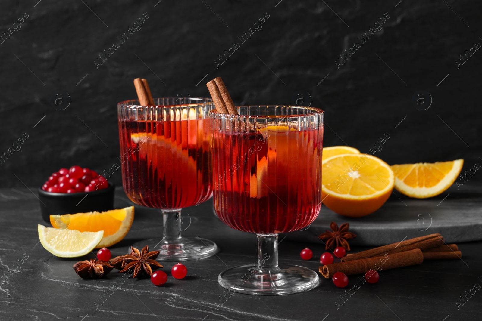 Photo of Aromatic punch drink and ingredients on black table