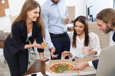 Photo of Office employees having pizza for lunch at workplace. Food delivery