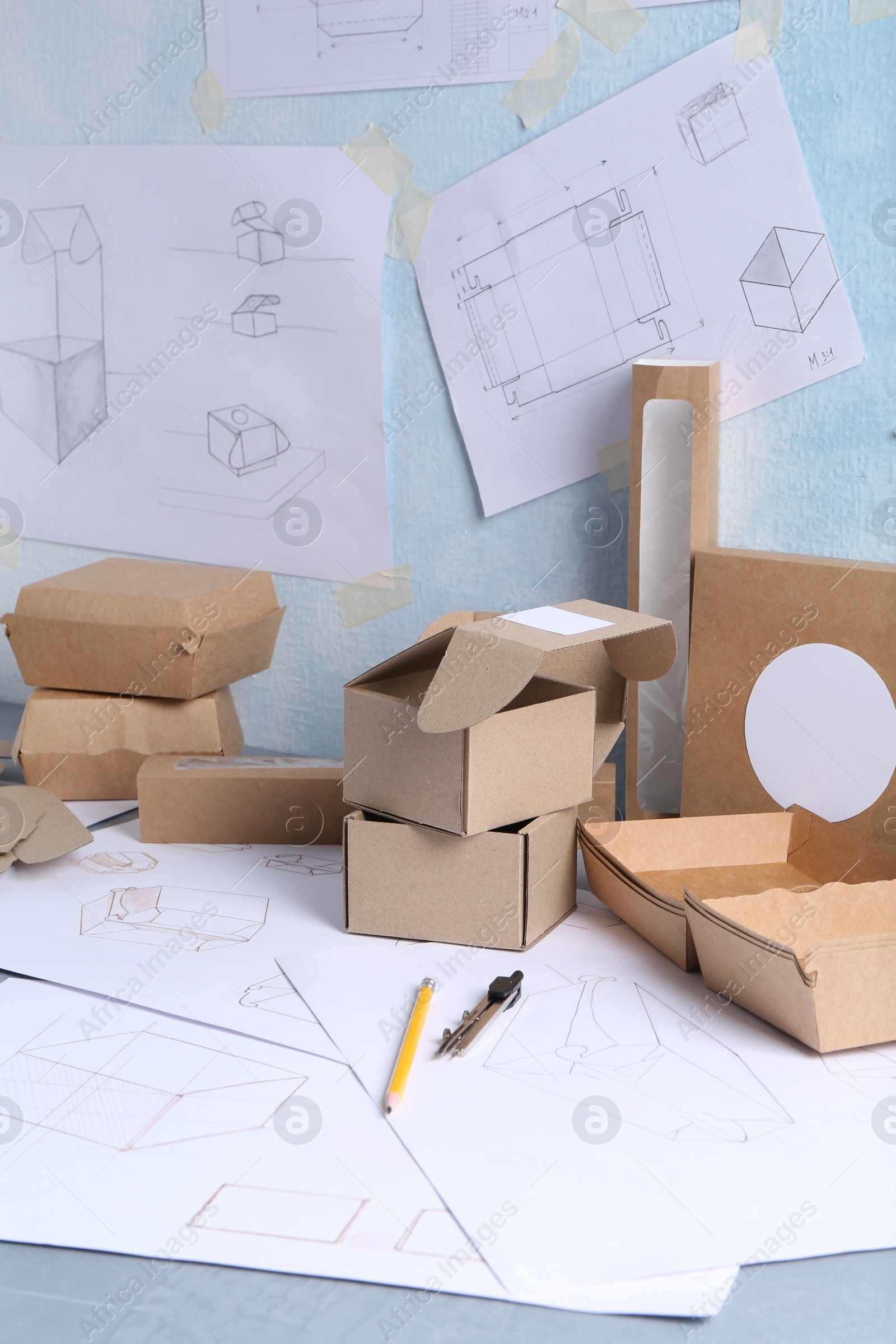 Photo of Creating packaging design. Drawings, boxes and stationery on table, closeup