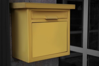 Photo of Yellow metal letter box on wall outdoors, closeup