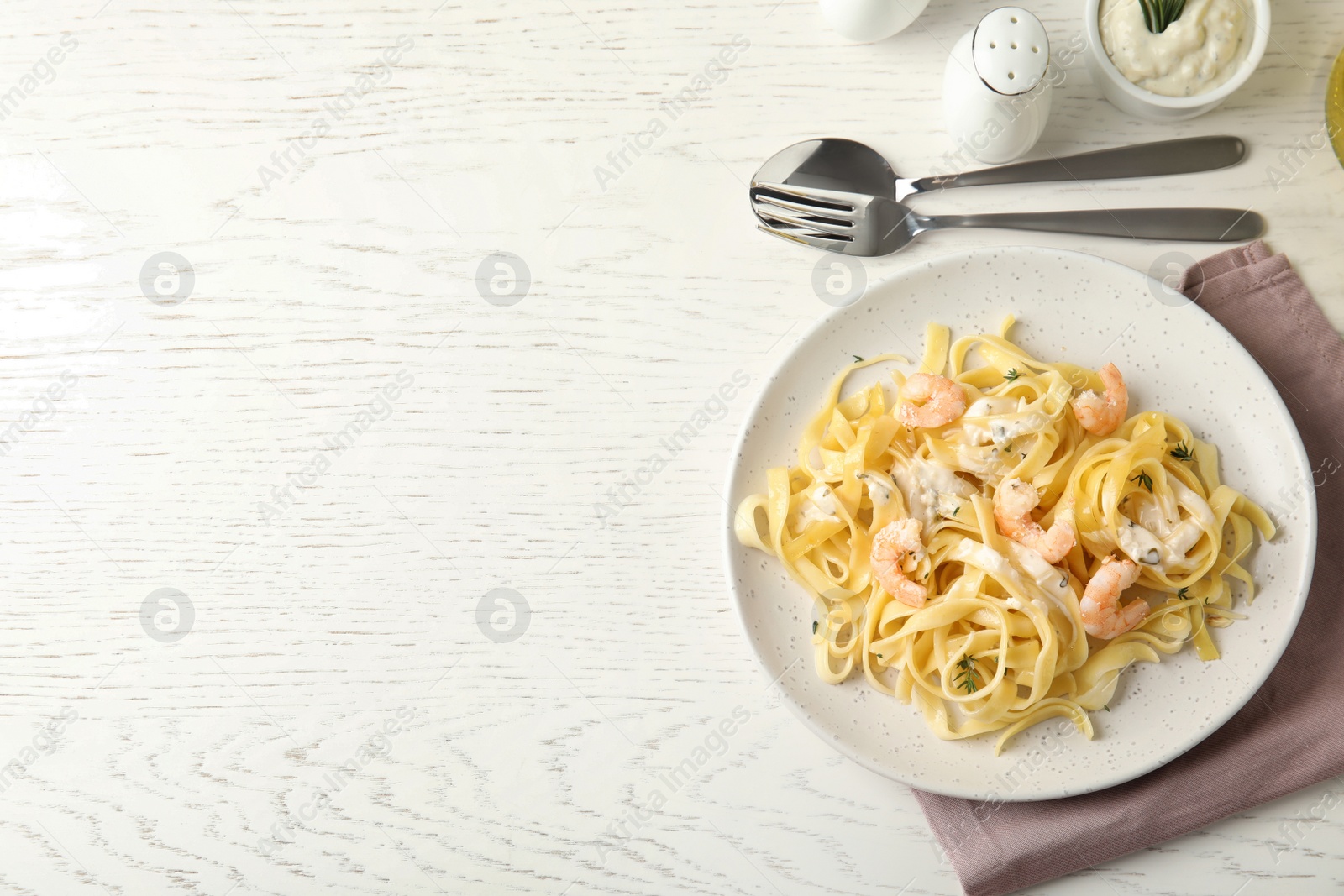 Photo of Delicious pasta with shrimps served on white wooden table, flat lay. Space for text